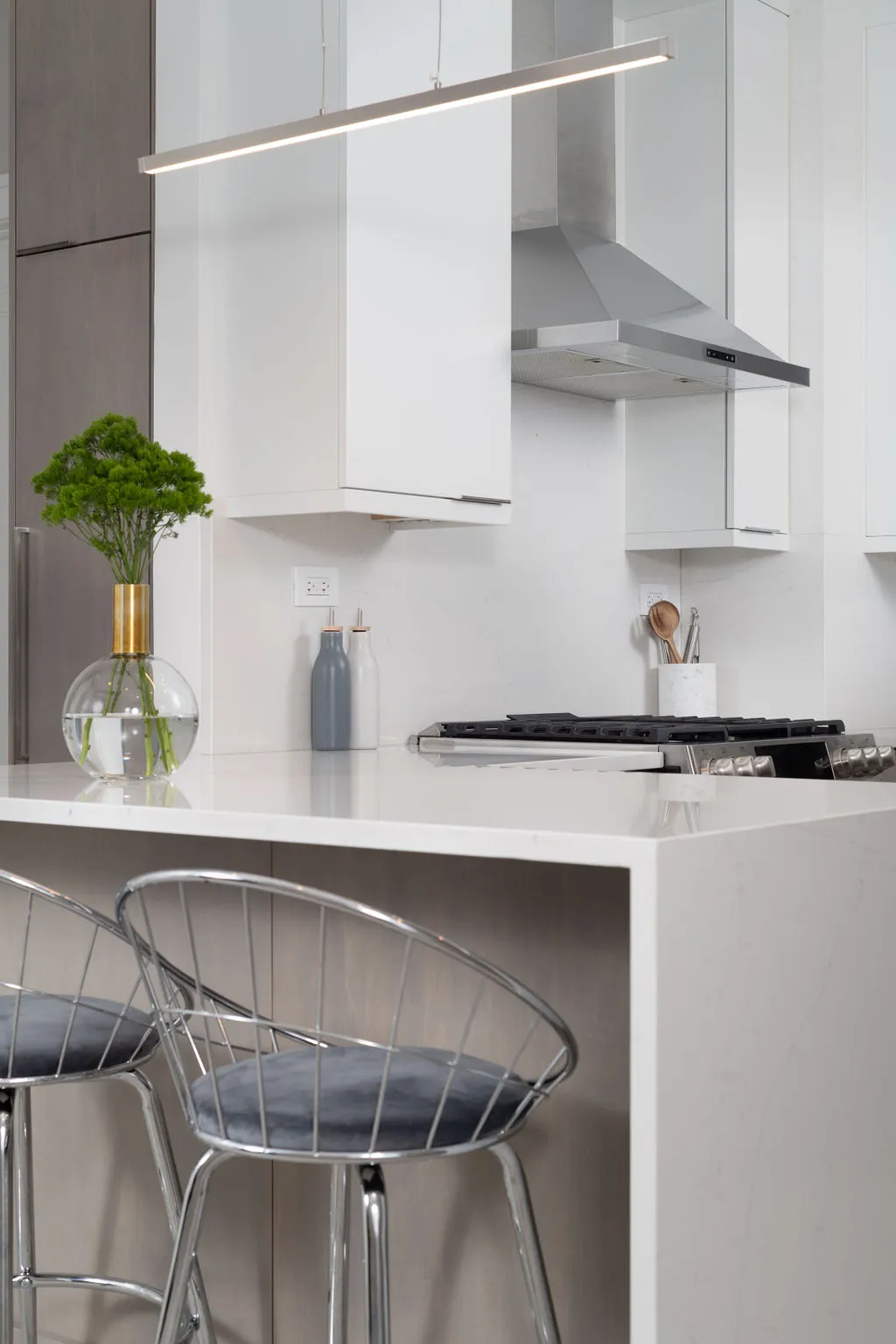 Herbal Touch in Modern Kitchen Contemporary kitchen with sleek cabinetry, marble countertops, and metallic chairs. Minimalist layout enhances stylish ambiance and modern functionality.