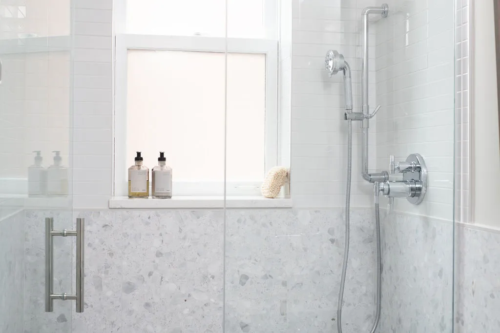 minimalist-marble-shower-space Contemporary powder room with geometric wallpaper, sleek marble countertop, and contrasting elements. Elegant pendant lighting enhances the modern aesthetic.