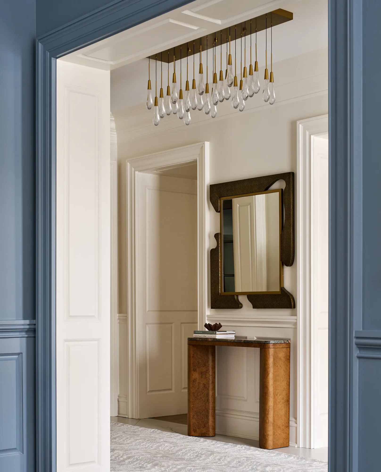 Contemporary hallway with neutral tones, artistic mirror, and elegant lighting.