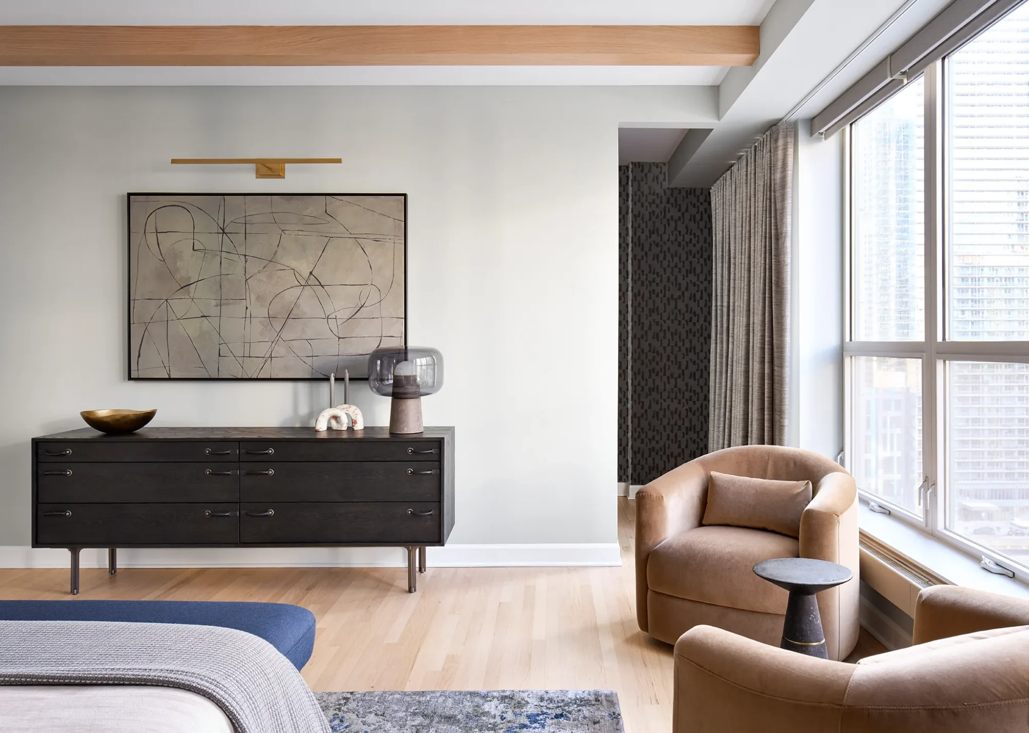 Luxury Chicago bedroom remodel with dark wood dresser, camel barrel chairs, and layered drapery, planned for daily function and light control.