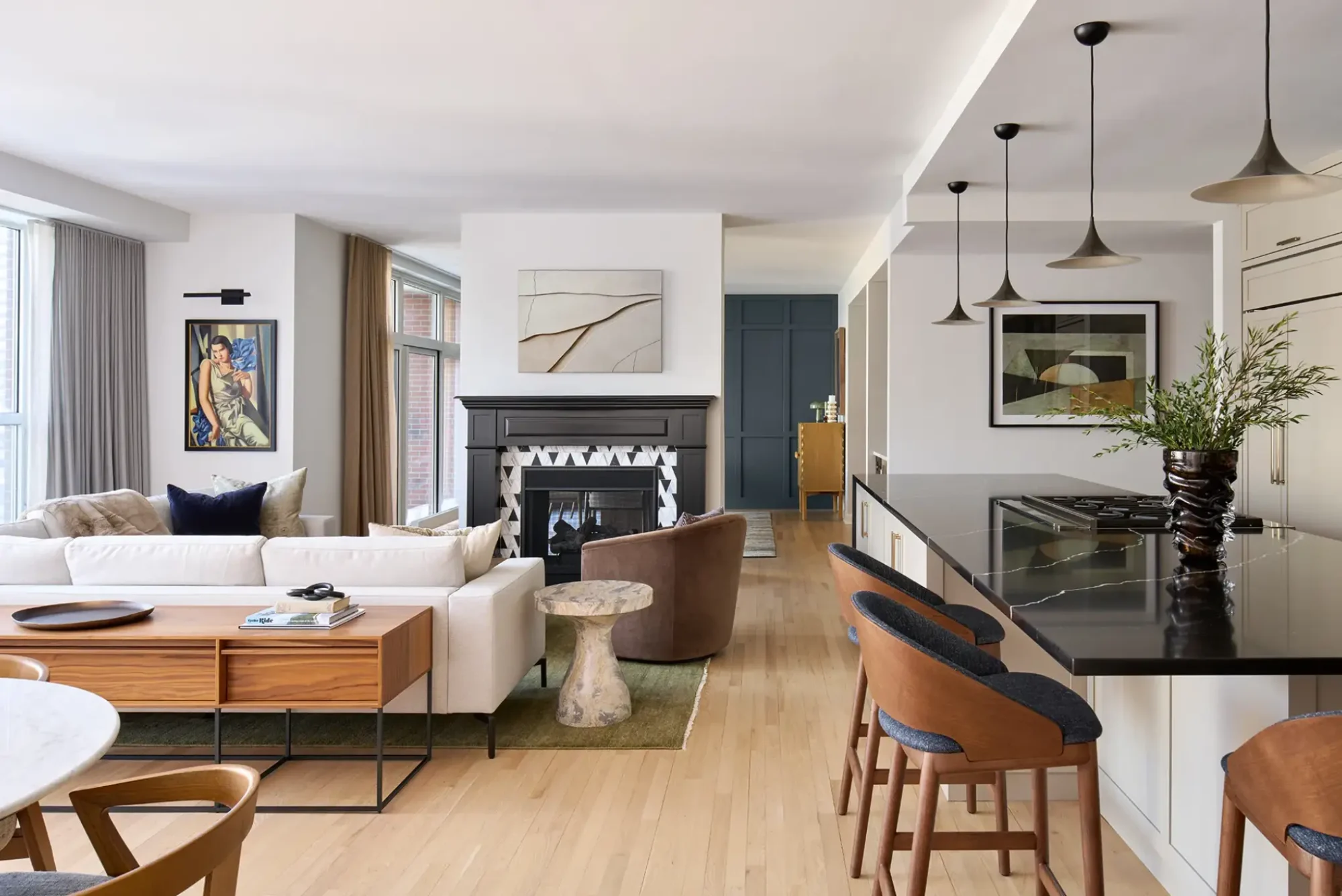Luxury open-concept living room in Chicago’s Streeterville with integrated kitchen, black stone counter, and a dark fireplace with geometric tile.