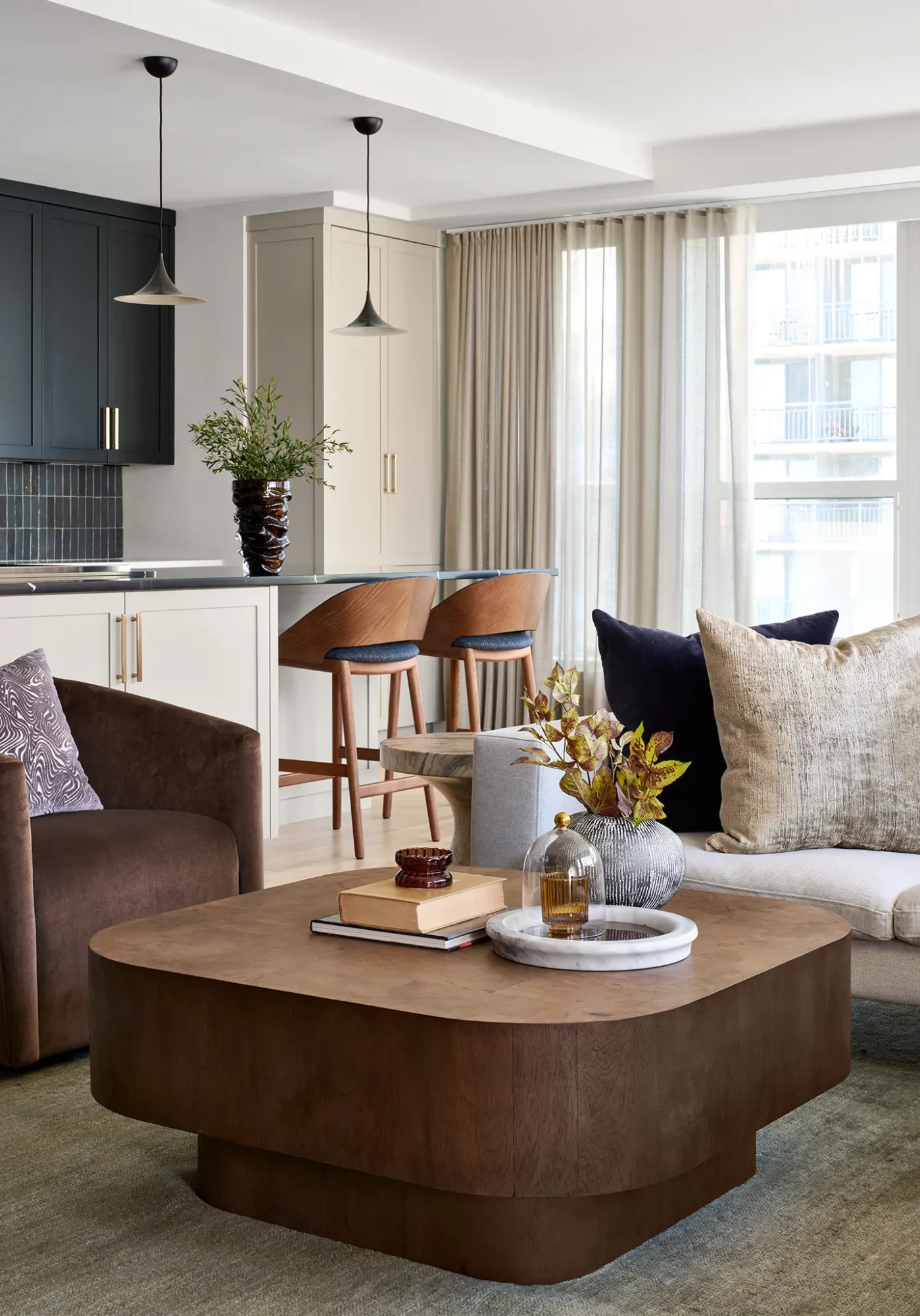 Luxury open-concept living room and kitchen in Streeterville—two-tone shaker cabinetry, brass pulls, light oak floors.