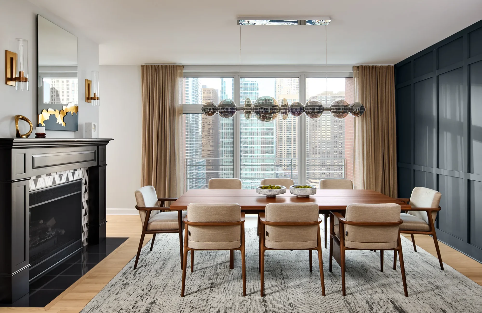 Luxury dining room in Chicago's Streeterville featuring a linear globe pendant, paneled accent wall, and fireplace with chevron tile.