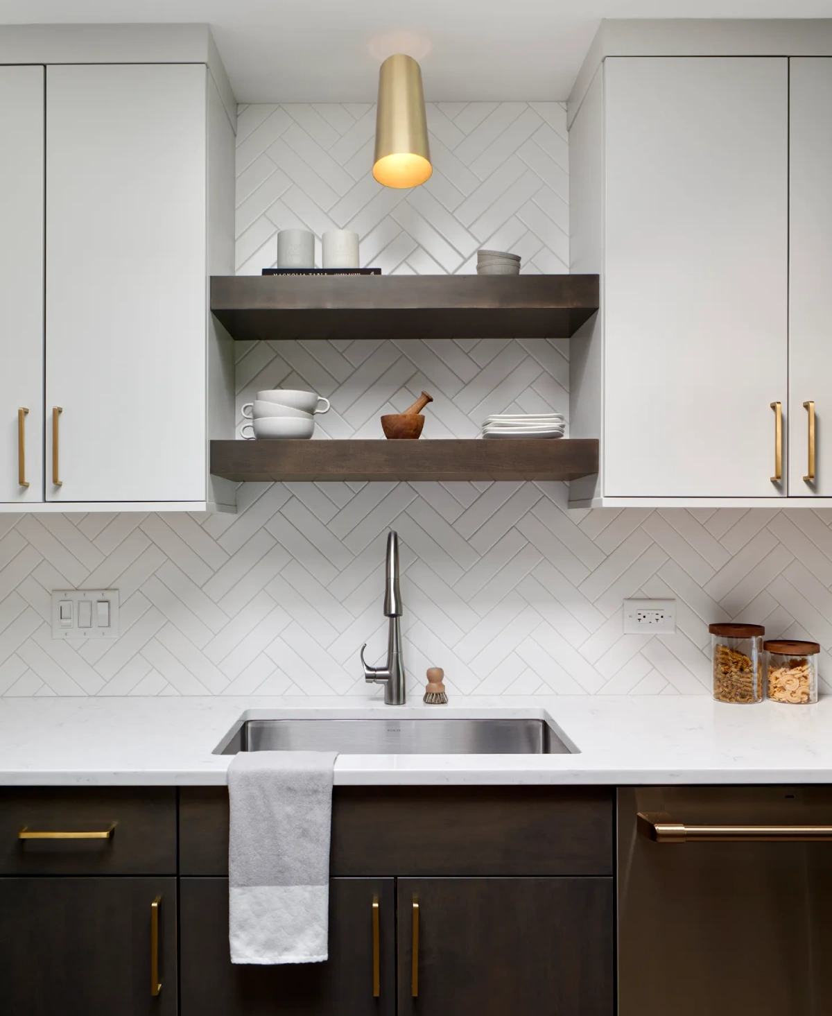 Contemporary kitchen with sleek cabinetry, chevron tile backsplash, floating shelves, and brass fixtures. Modern minimalist design with neutral tones.