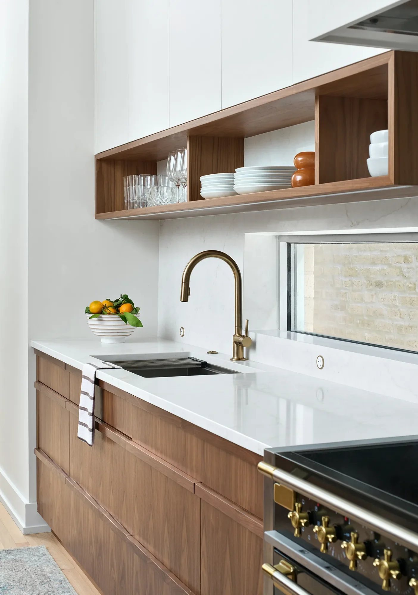 Modern Chicago kitchen design with white walls, warm walnut cabinetry, and marble countertop in West Town project.