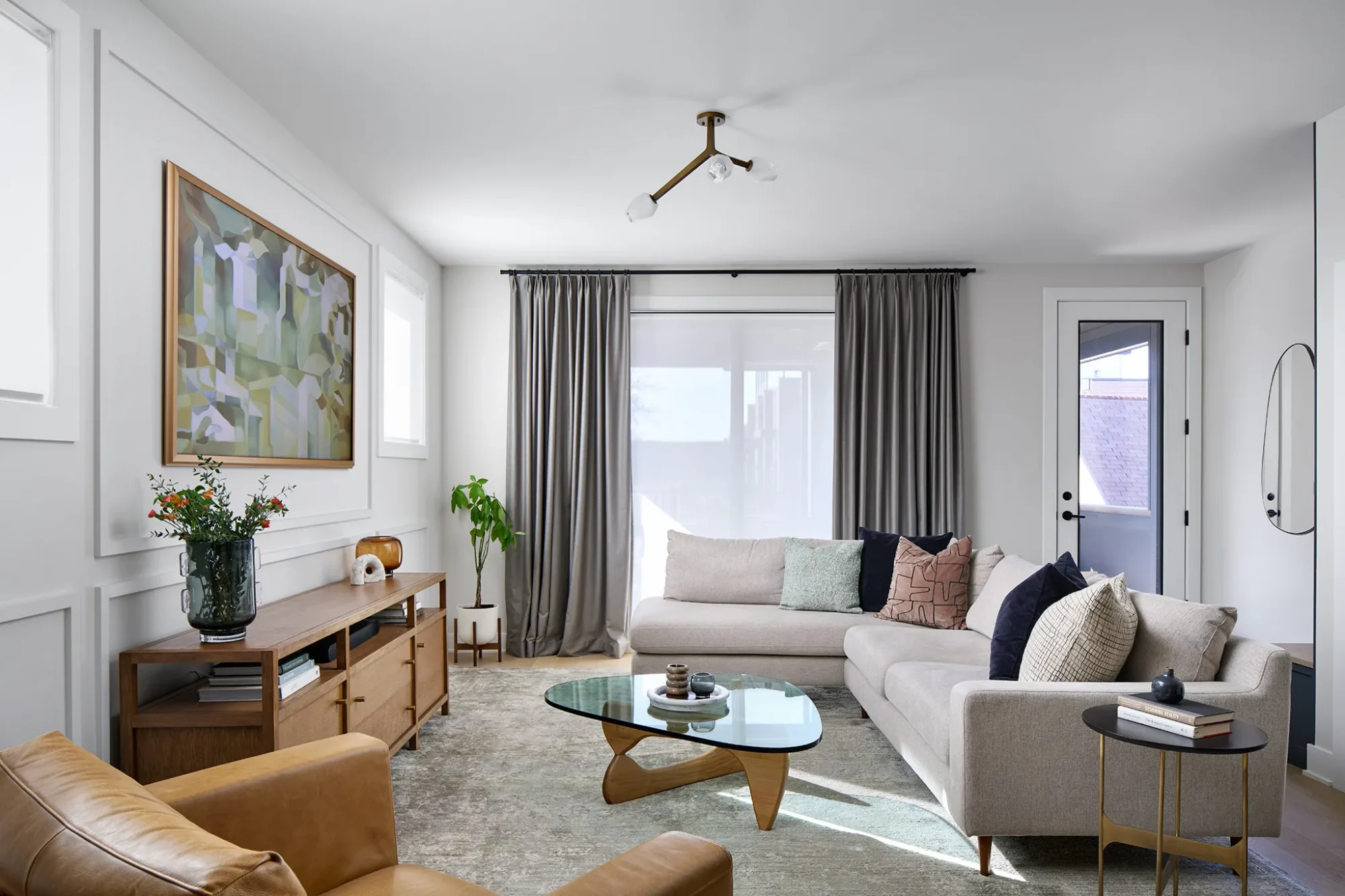 Velvet lounge seating and sculptural wood coffee table in a Lakeview Chicago living room with neutral palette, custom drapery, and layered textures