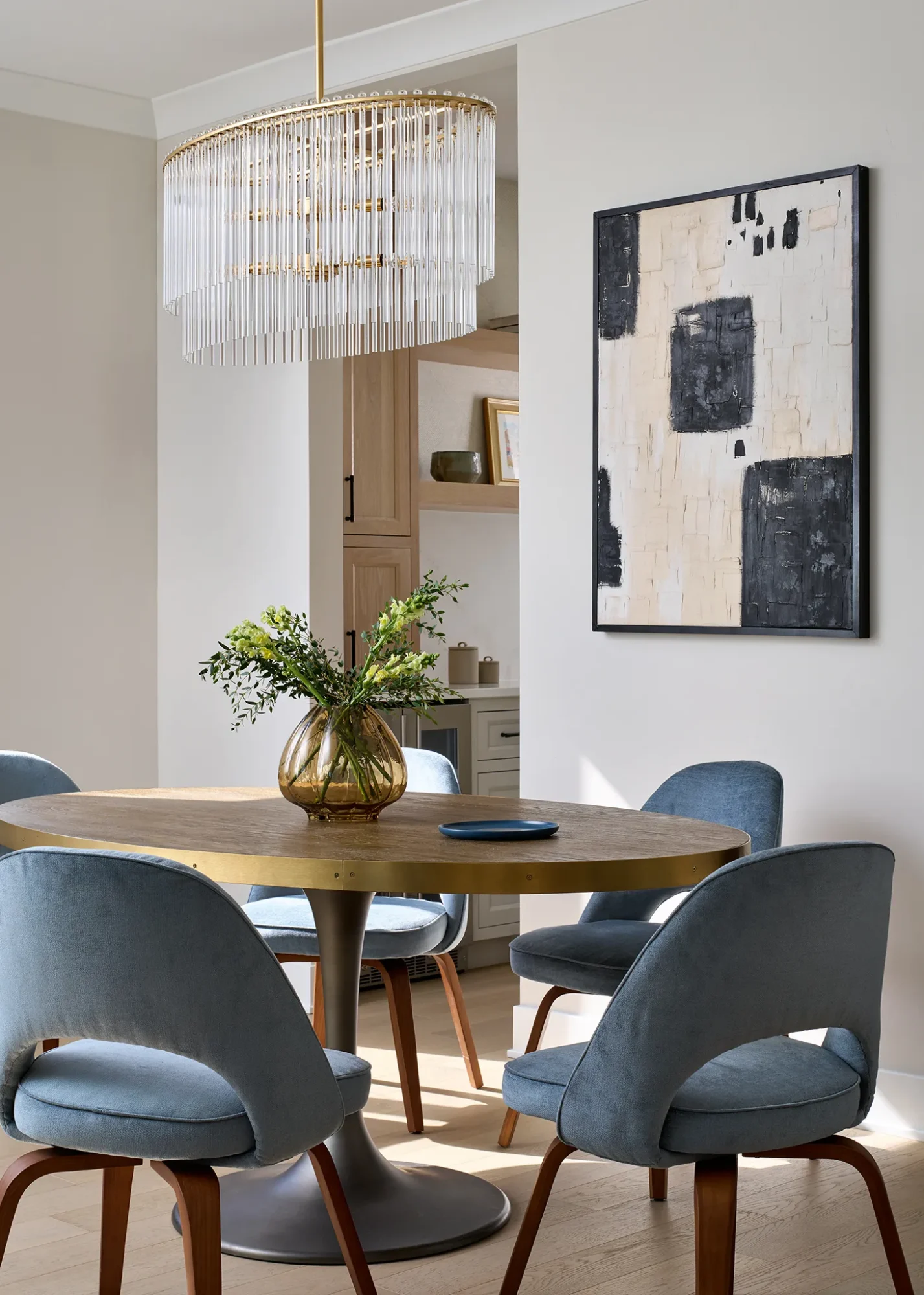 Dining room with brass chandelier, round wood table, and upholstered blue dining chairs in a modern design-build renovation