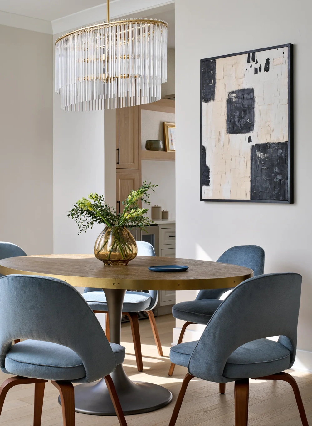 Dining room with brass chandelier, round wood table, and upholstered blue dining chairs in a modern design-build renovation
